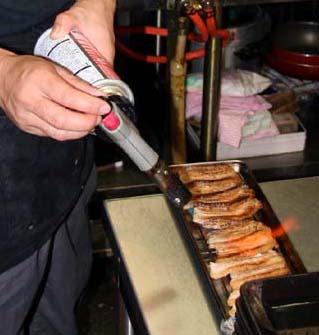 「醤飯」用の焼豚をバーナーで炙っているところ。